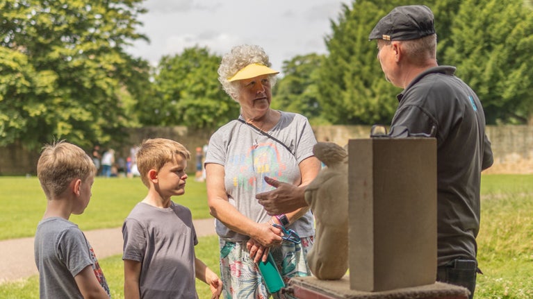 Stone mason showing a family how they create stone sculptures at Hardwick